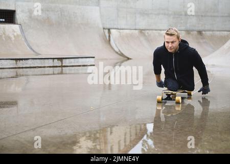 Jeune homme handicapé avec une longue planche dans un parc à roulettes Banque D'Images