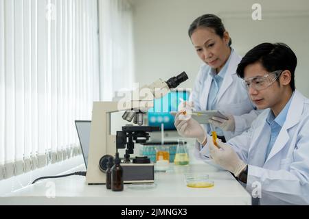 équipe de chercheurs en biochimie travaillant avec un microscope pour la mise au point de vaccins dans le domaine de la recherche pharmaceutique. Banque D'Images