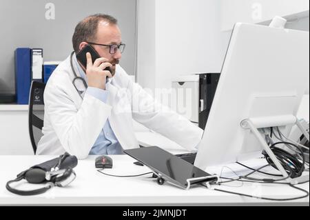 Médecin au bureau parlant au téléphone Banque D'Images