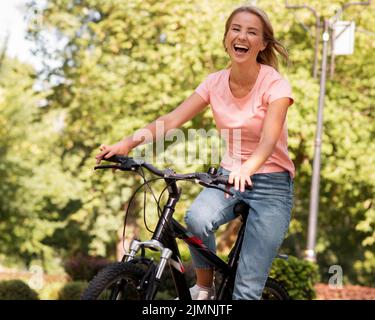 Femme à vélo riant Banque D'Images