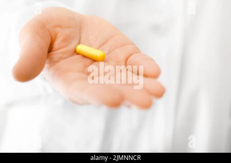 Une femme en forme de gommage blanc tient la pilule dans sa vue rapprochée de la main Banque D'Images