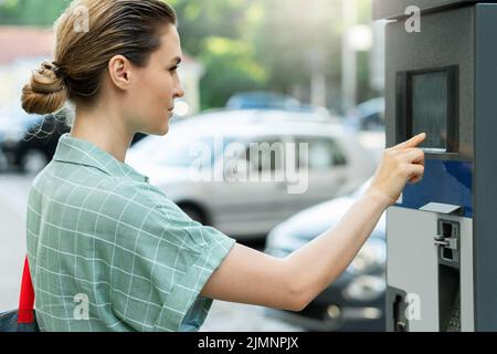 Belle femme payant dans la machine de parcage Banque D'Images