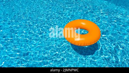 Anneau orange flottant dans la piscine bleue. Anneau gonflable, concept de repos Banque D'Images