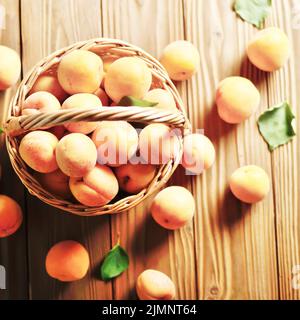 Vue de dessus du panier en osier avec des abricots mûrs sur table en bois Banque D'Images