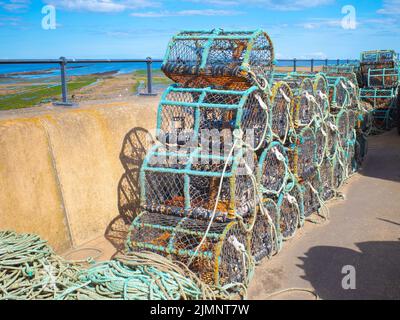 Des casiers à crabe ou homard empilés sur l'Esplanade, où les bateaux de pêche sont stationnés à Redcar North Yorkshire UK Banque D'Images