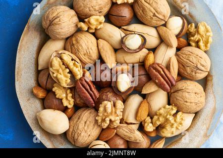 Bleu classique dans la nourriture. Mélange de noix sur plaque - noix, amandes, pacanes, macadamia Banque D'Images