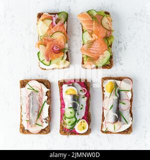 Smorrebrod de poisson salé, jeu de cinq sandwichs traditionnels danois. Pain de seigle noir Banque D'Images