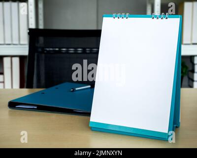 Modèle de calendrier de bureau blanc à rabat style vertical près du dossier de documents sur une table en bois, pour la conception d'entreprise. Table de bureau en spirale Banque D'Images