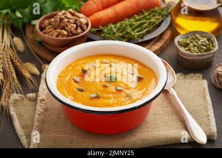 Soupe à la crème de citrouille avec graines et noix, carottes, vue latérale avec feuilles d'automne pour l'atmosphère Banque D'Images