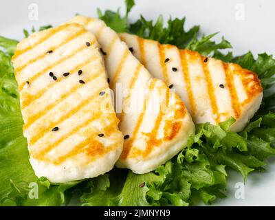 Halloumi grillé, fromage macro frit avec salade de laitue. Alimentation équilibrée, assiette blanche, vue latérale Banque D'Images