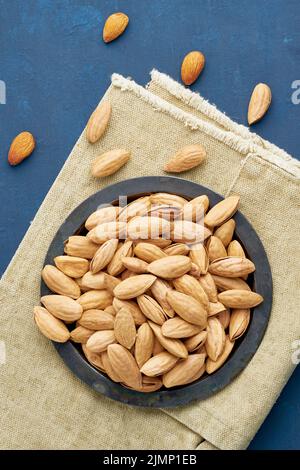 Plaque de vue supérieure avec amandes en endocarpe, bol avec drupe en coquille sur une serviette en lin Banque D'Images