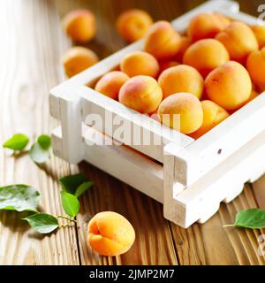 Caisse en bois blanc avec des abricots sur table Banque D'Images