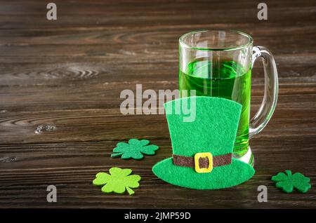 La journée de St Patricks est agrémentée d'une pinte de bière verte sur une table en bois avec des shamrocs en feutre faits à la main. Espace-copie Banque D'Images