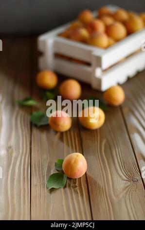 Caisse en bois blanc avec des abricots sur table Banque D'Images