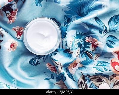 Cosmétiques pour le soin de la peau, pot hydratant crème visage sur fond floral bleu, flatte de produit de beauté Banque D'Images