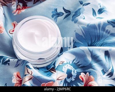 Cosmétiques pour le soin de la peau, pot hydratant crème visage sur fond floral bleu, flatte de produit de beauté Banque D'Images