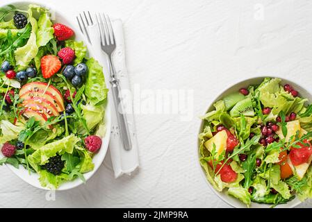 Salades fraîches avec laitue et fruits sur fond blanc vue du dessus avec espace pour le texte. Une alimentation saine. Banque D'Images