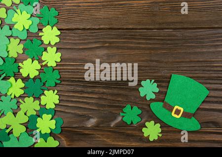 Happy Saint Patrick's immersive de hat à la main et les feuilles de trèfle irlandais sur fond de bois. Banque D'Images