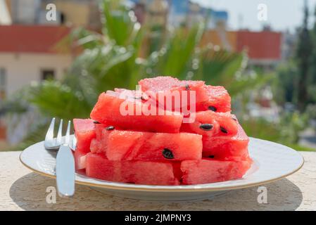 Melon d'eau mûr coupé en tranches sur une assiette et vue sur les palmiers. Banque D'Images