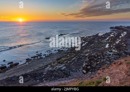 Lever du soleil à Filey Brigg, longue péninsule étroite sur la côte du North Yorkshire près de Filey en Angleterre. Banque D'Images
