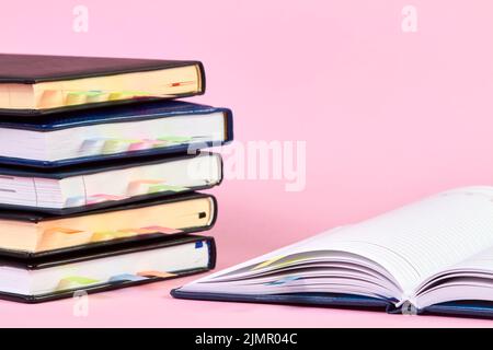 Gros plan d'un bloc-notes ouvert avec des marqueurs de page adhésifs colorés sur l'arrière-plan d'une pile de blocs-notes de bureau Banque D'Images