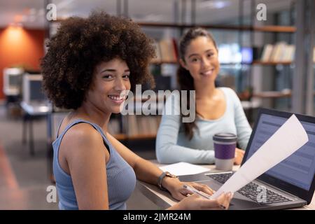 Portrait d'une femme d'affaires biraciale souriante avec une collègue hispanique travaillant ensemble au bureau Banque D'Images