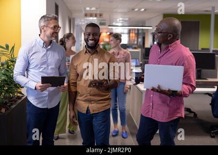 Souriant hommes d'affaires multiraciaux discutant tout en se tenant ensemble contre les femmes d'affaires au pouvoir Banque D'Images