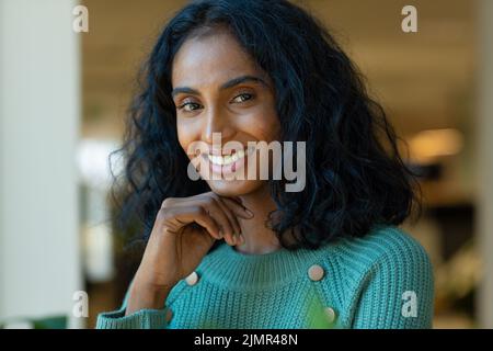 Portrait de jeune femme biracial souriante avec cheveux noirs sur le lieu de travail Banque D'Images