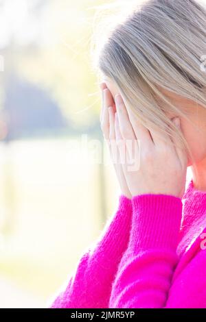 Triste fatigué jeune belle blonde femme avec son visage dans les mains étant effrayés, ayant l'anxiété ou mal de tête migraine ou depre Banque D'Images