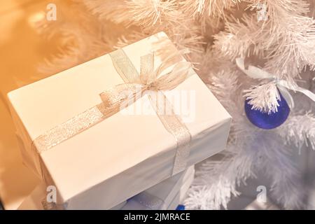 Noël boîtes blanches avec rubans blancs sous un arbre blanc de Noël avec des ballons bleus. Carte de vœux de Noël et du nouvel an, vacances d'hiver. Photo de haute qualité Banque D'Images