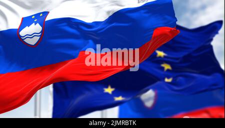 Détail du drapeau national de la Slovénie qui agite dans le vent avec un drapeau flou de l'Union européenne Banque D'Images