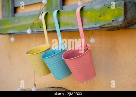 Jardinière en métal coloré ou jardinière en forme de clôture avec crochets, accrochée au mur avec des ampoules décoratives. Banque D'Images