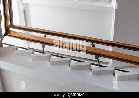 Escalier en pierre blanche avec garde-corps en bois contre plafond blanc. Vue de dessous Banque D'Images