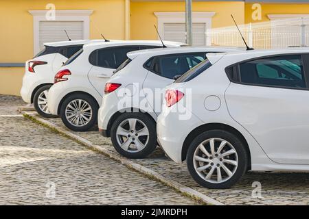 Quatre voitures semblables à hayon blanc garées dans la rue dans une ville typique d'Europe Banque D'Images