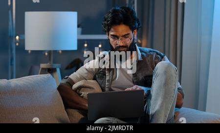 Homme arabe réfléchi indépendant indien barbu homme adulte pensant à un projet informatique solution de recherche de problèmes regardant sur ordinateur portable à la maison doub Banque D'Images