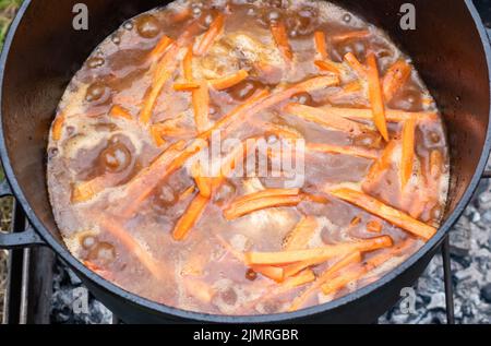 Tranches de carottes d'orange qui se pichent dans un bouillon dans un chou-fleur Banque D'Images