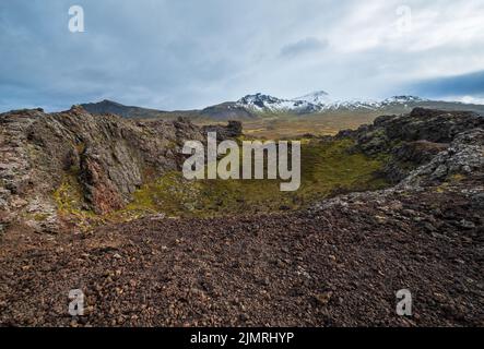 Vue volcanique spectaculaire depuis le cratère de Saxholl, péninsule de Snaefellsnes, Islande de l'Ouest. Le volcan enneigé de Snaefellsjokull est de loin. Banque D'Images