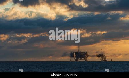 Une plate-forme de forage de pétrole et de gaz se dresse au large de la rive de Dauphin Island, en Alabama, sur une image composite. Banque D'Images