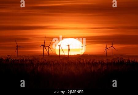 Coucher de soleil derrière le parc éolien de Tick Fen Banque D'Images