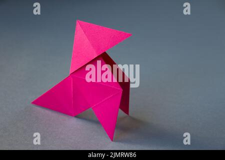 Origami de poule de papier rose isolé sur fond gris Banque D'Images