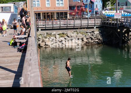 Les jeunes garçons sautent de la promenade dans l'eau en contrebas dans le quartier historique de la rue Creek, construit au-dessus du ruisseau Ketchikan à Ketchikan, en Alaska. Banque D'Images