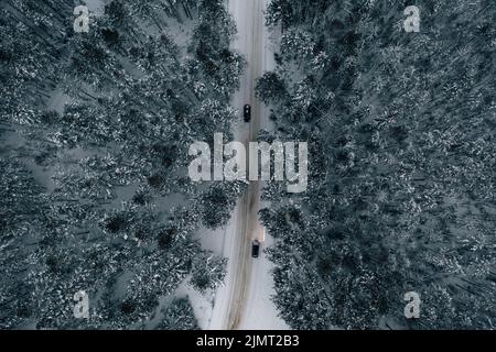 Vue aérienne de la route enneigée avec des voitures, forêt d'hiver Banque D'Images