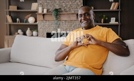 L'homme d'amant affectueux africain doux adulte senior volontaire américain faire le coeur avec les doigts exprimant l'homme en bonne santé ressent l'amour de charité Banque D'Images
