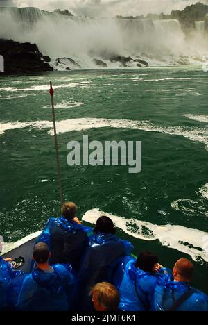 Les passagers sur le Maid of the Mist à Niagara Falls, en Ontario, passent devant les chutes américaines portant des ponchos imperméables bleus pour les protéger contre les projections Banque D'Images