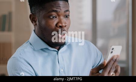 Un homme africain surpris un homme du millénaire 30s parle à distance sur téléphone mobile un homme américain adorable et adulte fait un appel vidéo choqué par soudain Banque D'Images