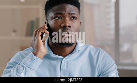 Homme d'affaires afro-américain professionnel homme analyste homme répondre à l'appel entrant parler au téléphone dans le bureau à domicile heureux choqué surpris jeune gars obtenir Banque D'Images