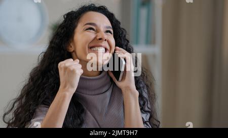 Jolie fille arabe souriante jeune femme parle par téléphone mobile profiter de la conversation sans fil dire des commérages choqué joyeuse heureuse femme millénaire heureuse d'entendre Banque D'Images