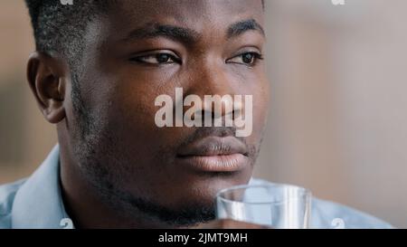 Gros plan Afrique millénaire homme boire pur eau froide verre liquide sain souffrir de chaud prendre l'habitude quotidienne hydrate soif américain tho Banque D'Images