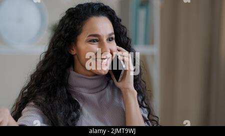 Jolie fille arabe souriante jeune femme parle par téléphone mobile profiter de la conversation sans fil dire des commérages choqué joyeuse heureuse femme millénaire heureuse d'entendre Banque D'Images