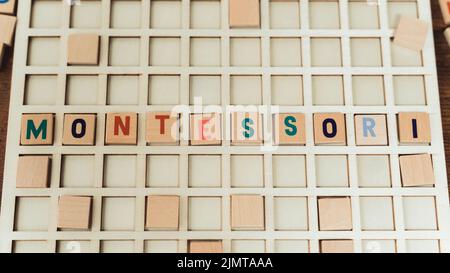 Méthode italienne connue d'éducation. Lettres en bois colorées sur une planche créant le mot MONTESSORI. Photo de haute qualité Banque D'Images